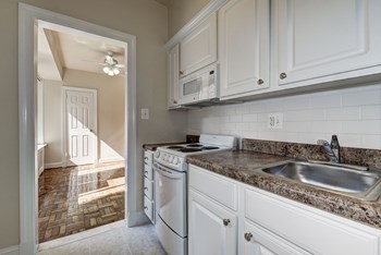 kitchen with stone countertops and white cabinets and appliances at Park Crescent Apartments in Washington, DC